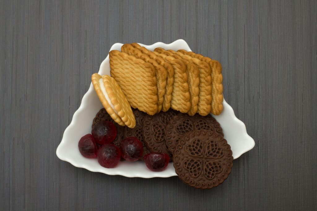 Close-up of various biscuits with colorful gumdrops on a decorative plate.