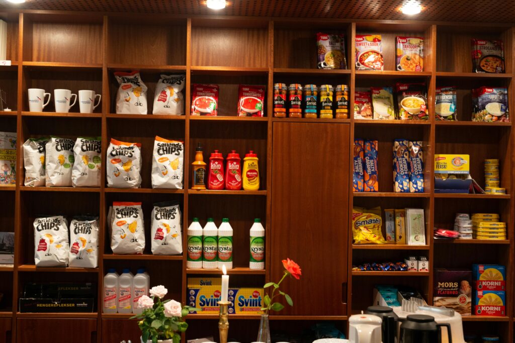 Wide array of packaged groceries neatly arranged on wooden shelves in a store setting.