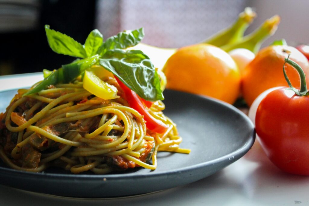 A plate of spaghetti garnished with basil and fresh vegetables, showcasing Italian cuisine.