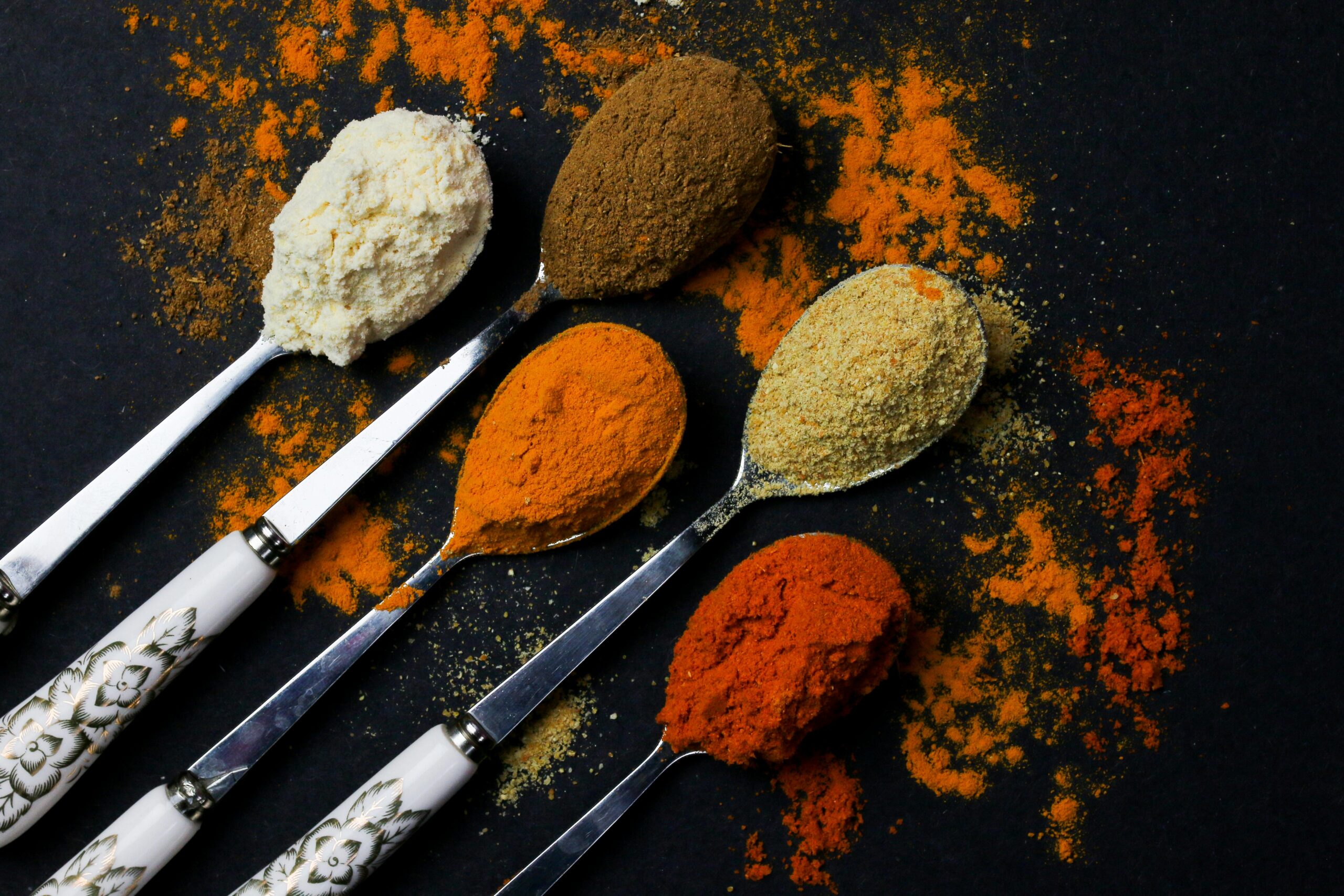 A vibrant array of spices on decorative spoons, showcasing culinary diversity.