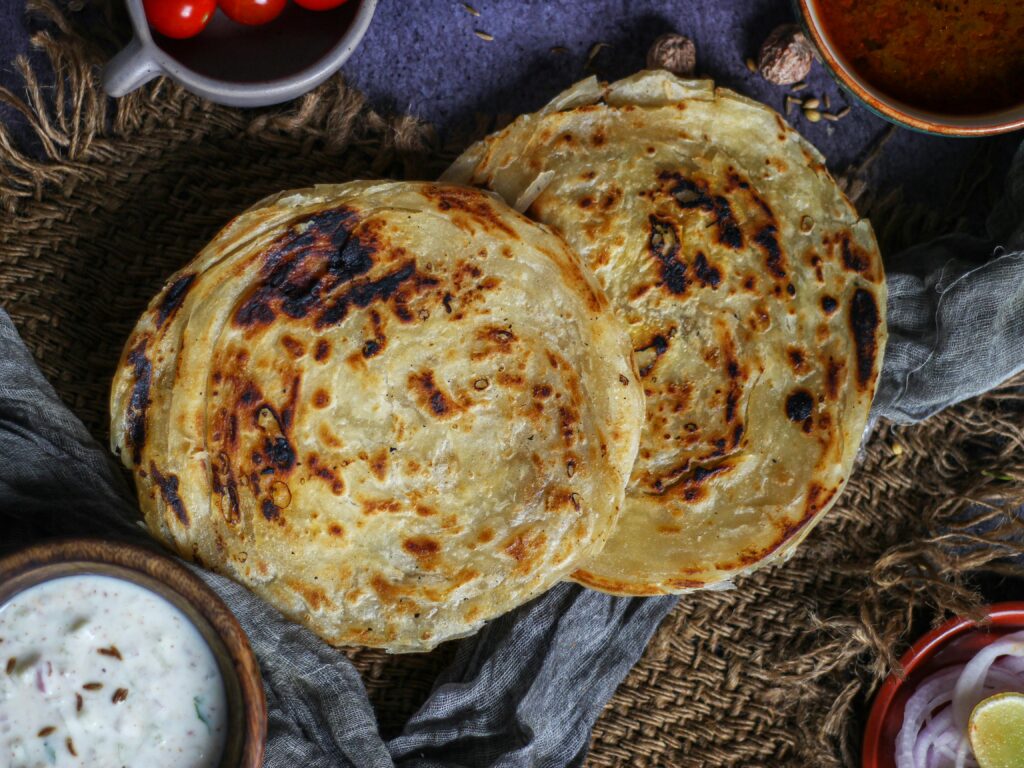 Delicious Indian parotta served with side dishes, highlighting traditional flavors and textures.